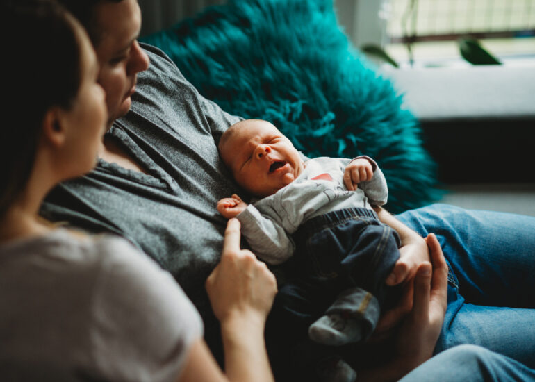 ziewające niemowlę w objęciach taty