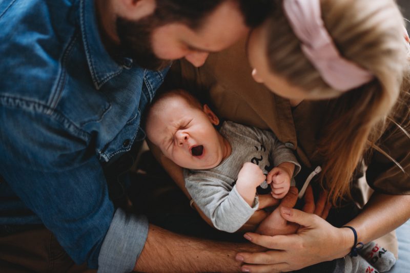 ziewające niemowlę w objęciach rodziców